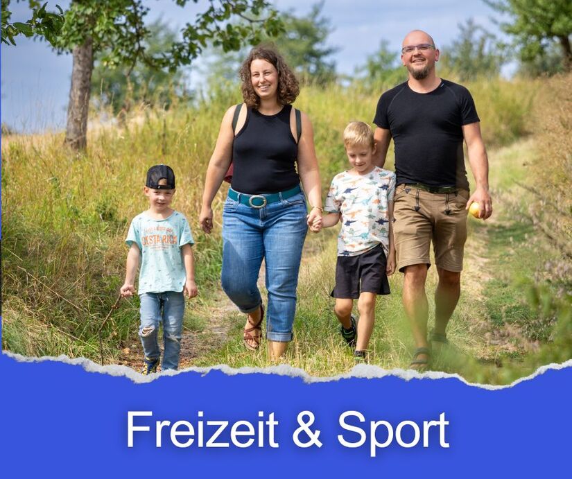 Familie mit zwei Kindern beim Wandern auf einem Feldweg mit Bäumen